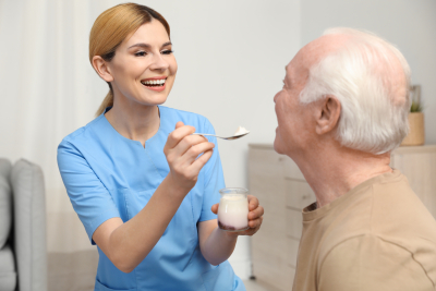 nurse feeding senior woman with yogurt